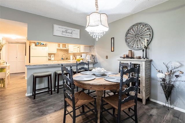 dining area featuring dark hardwood / wood-style flooring, sink, and a chandelier