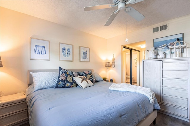 bedroom with ceiling fan, dark hardwood / wood-style floors, and a textured ceiling