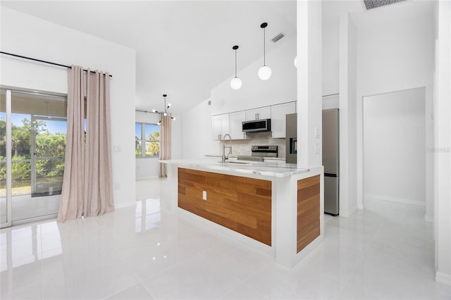 kitchen with visible vents, an island with sink, stainless steel appliances, white cabinetry, and pendant lighting