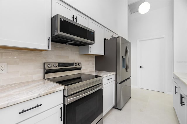 kitchen featuring light stone countertops, white cabinetry, appliances with stainless steel finishes, and backsplash