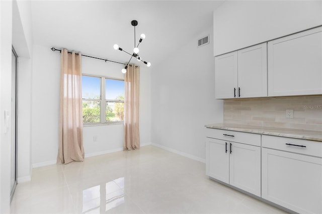 unfurnished dining area featuring lofted ceiling, baseboards, visible vents, and a chandelier