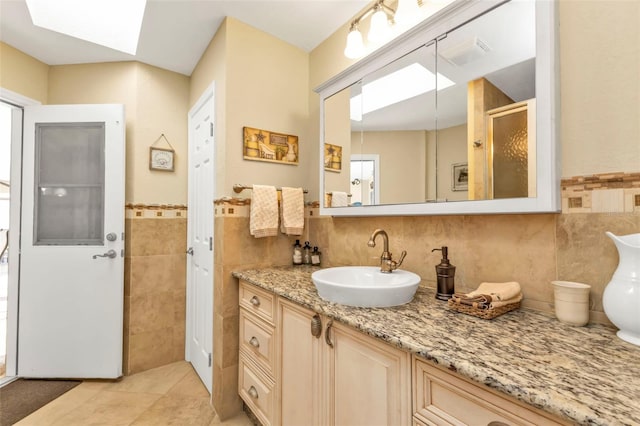 bathroom featuring tile patterned floors, vanity, a skylight, and tile walls