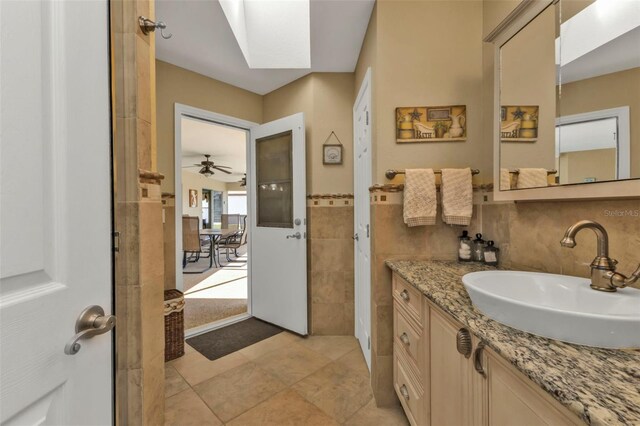 bathroom featuring vanity, a skylight, tile patterned flooring, and tile walls