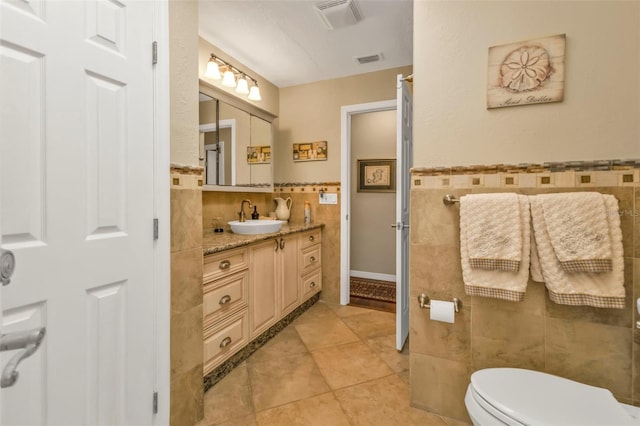 bathroom featuring tile walls, vanity, tile patterned flooring, and toilet