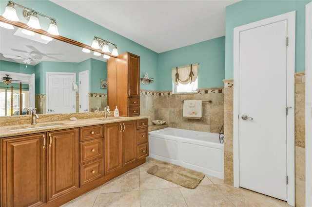 bathroom with tile walls, a tub to relax in, vanity, ceiling fan, and tile patterned floors