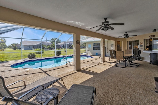 view of swimming pool with a yard, a patio, ceiling fan, and glass enclosure