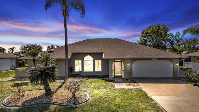 ranch-style home featuring a garage and a yard