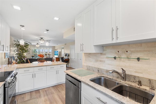 kitchen featuring sink, appliances with stainless steel finishes, light stone countertops, white cabinets, and light wood-type flooring