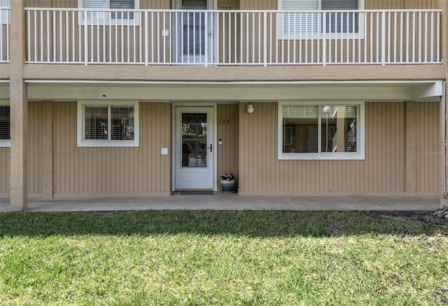 property entrance featuring a patio, a balcony, and a lawn