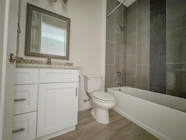 full bathroom featuring wood-type flooring, toilet, tiled shower / bath combo, and vanity