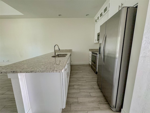 kitchen with sink, white cabinetry, a kitchen island with sink, stainless steel appliances, and light stone countertops