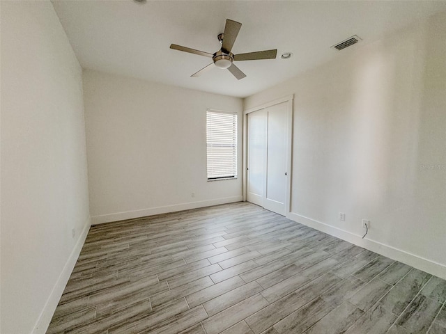 empty room with ceiling fan and light hardwood / wood-style flooring