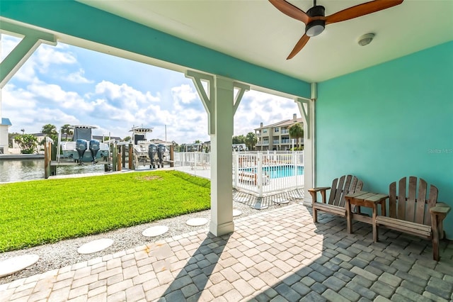 view of patio featuring a water view, a dock, a community pool, and ceiling fan