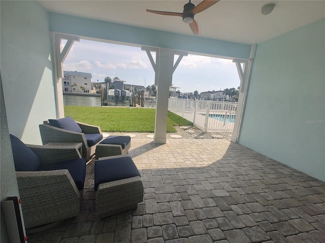 view of patio / terrace with a water view, a ceiling fan, and a fenced in pool