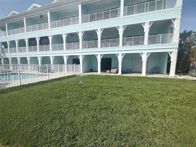 back of property featuring a patio, a community pool, and a lawn