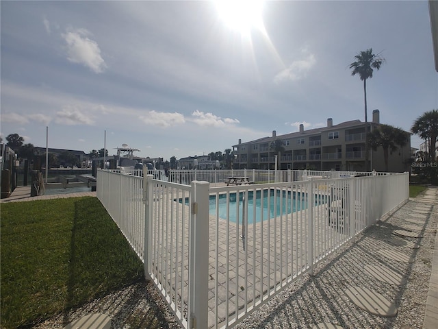 community pool featuring a patio area, a dock, fence, and boat lift