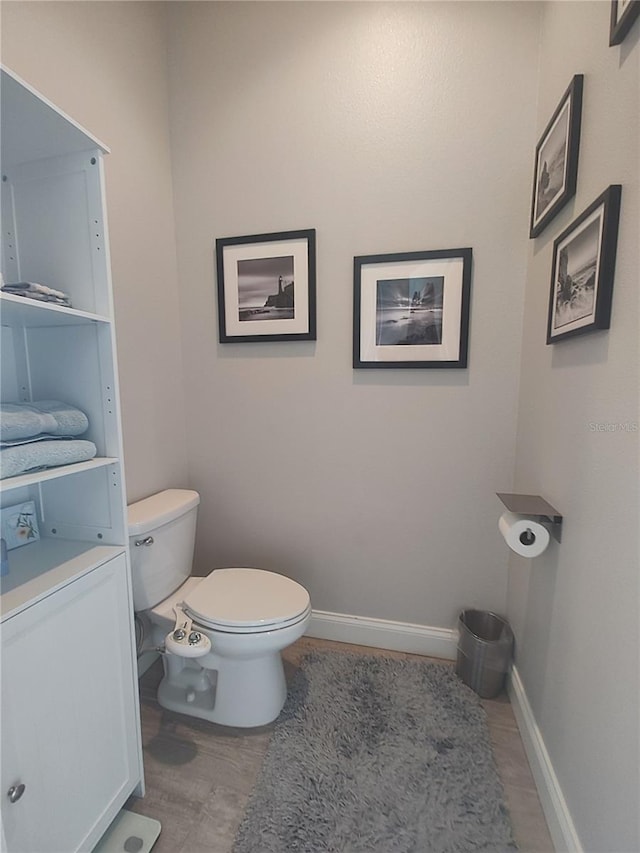 bathroom featuring toilet, wood finished floors, and baseboards