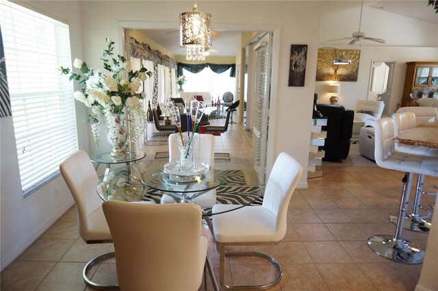 dining space with ceiling fan with notable chandelier, light tile patterned floors, and lofted ceiling