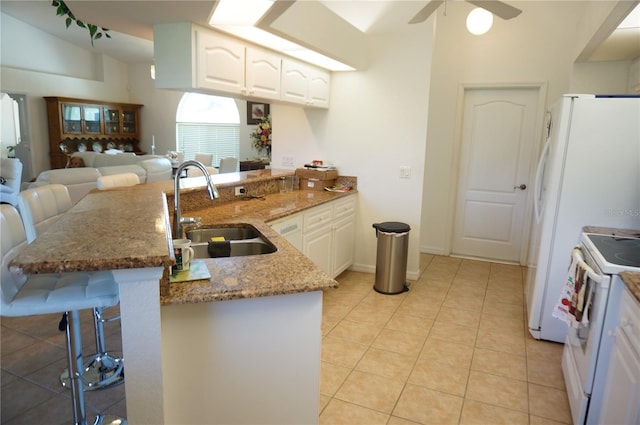 kitchen with white cabinetry, sink, a breakfast bar, and kitchen peninsula