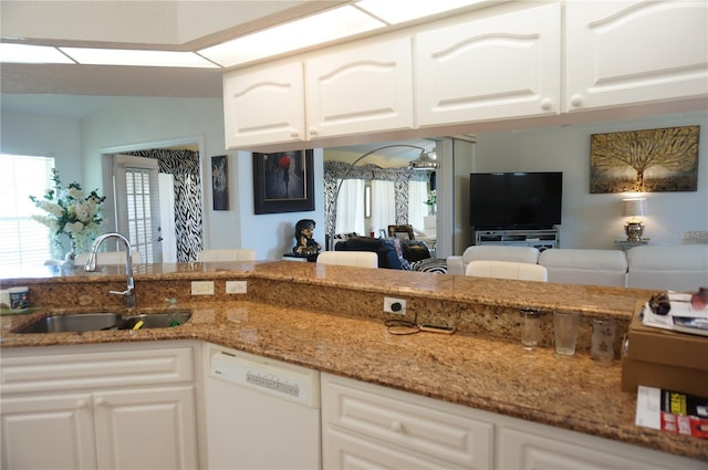 kitchen with white dishwasher, sink, white cabinetry, and stone counters