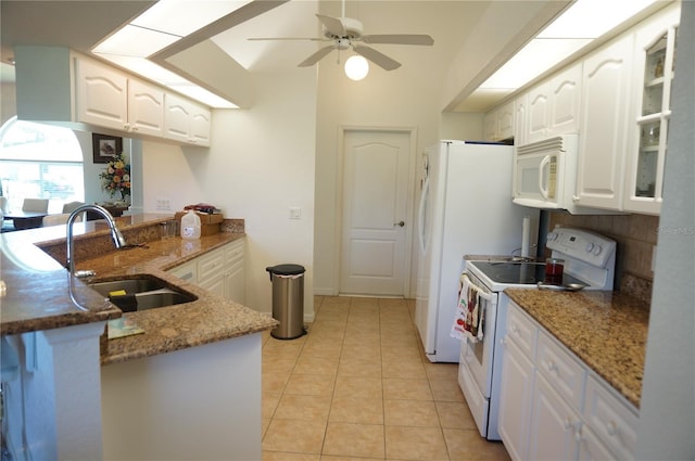 kitchen featuring white cabinetry, sink, dark stone countertops, kitchen peninsula, and white appliances