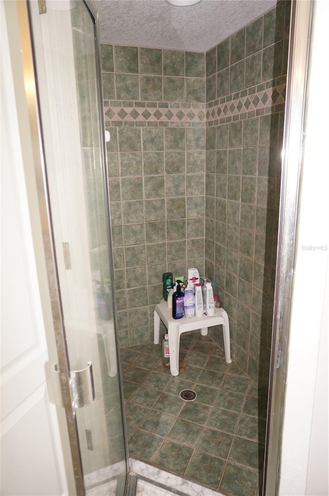 bathroom with a shower with door and a textured ceiling