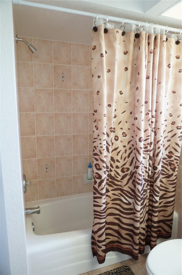 bathroom with tile patterned floors, shower / bath combo with shower curtain, and toilet