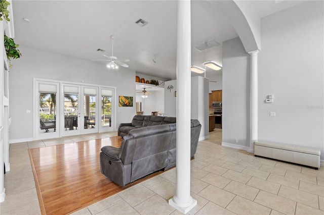 living area with ceiling fan, arched walkways, light tile patterned flooring, visible vents, and ornate columns