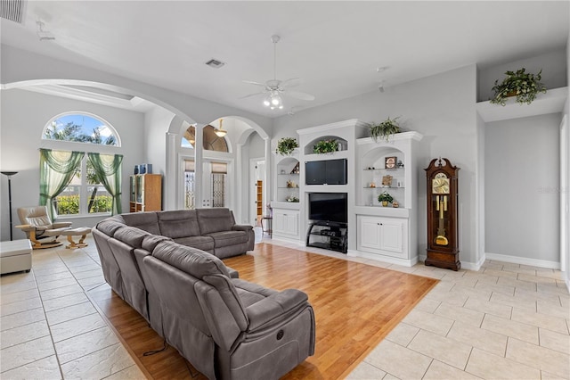 living area with arched walkways, light tile patterned floors, visible vents, and a ceiling fan