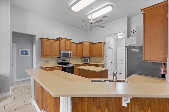 kitchen with visible vents, a peninsula, stainless steel appliances, light countertops, and a sink