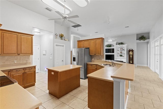 kitchen featuring a ceiling fan, a center island, light countertops, and stainless steel fridge with ice dispenser