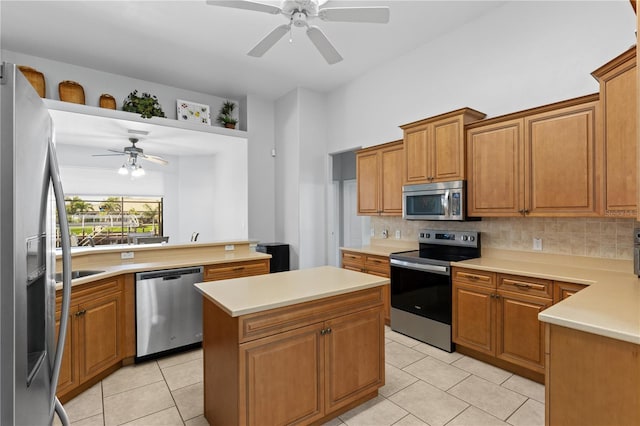 kitchen with stainless steel appliances, light countertops, a kitchen island, and backsplash