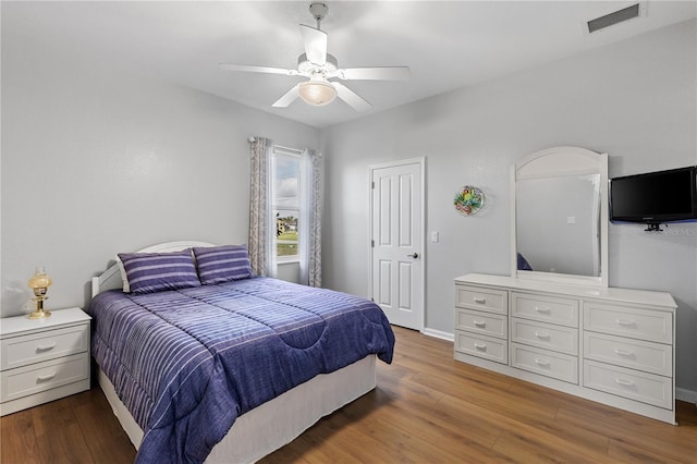 bedroom featuring baseboards, ceiling fan, visible vents, and wood finished floors