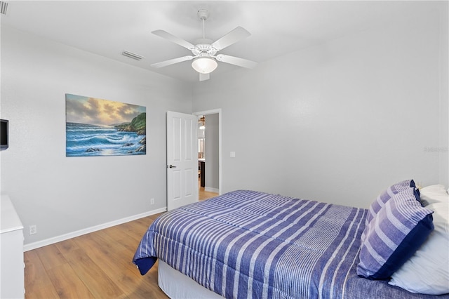 bedroom with a ceiling fan, visible vents, baseboards, and wood finished floors