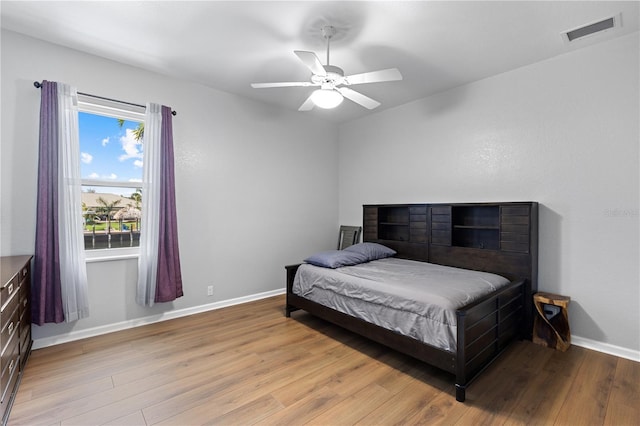 bedroom with a ceiling fan, light wood-type flooring, visible vents, and baseboards