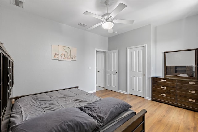 bedroom featuring light wood finished floors, baseboards, visible vents, and a ceiling fan