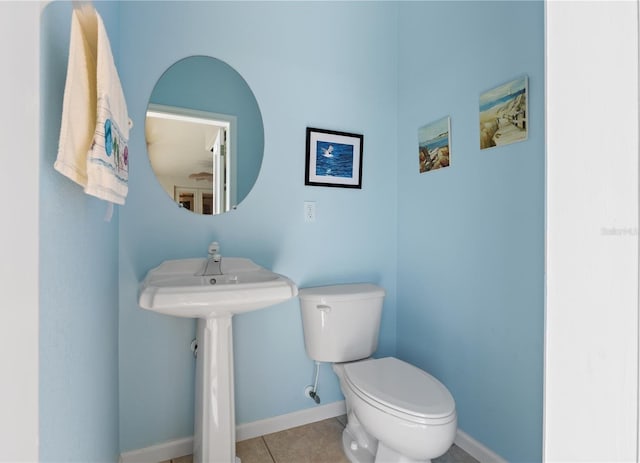 bathroom featuring toilet, tile patterned flooring, baseboards, and a sink