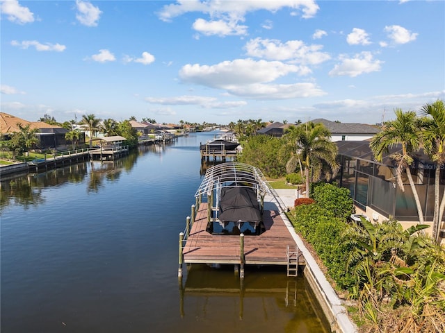 view of dock with glass enclosure, a water view, and boat lift