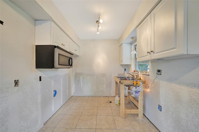 kitchen featuring white cabinetry, light tile patterned floors, track lighting, and sink