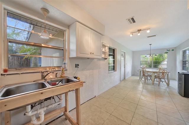 kitchen featuring light tile patterned floors, sink, white cabinetry, track lighting, and decorative light fixtures