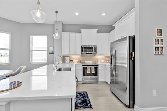 kitchen with pendant lighting, sink, white cabinetry, and stainless steel appliances