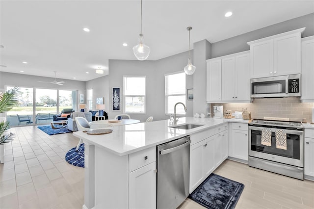 kitchen with pendant lighting, stainless steel appliances, sink, and white cabinets