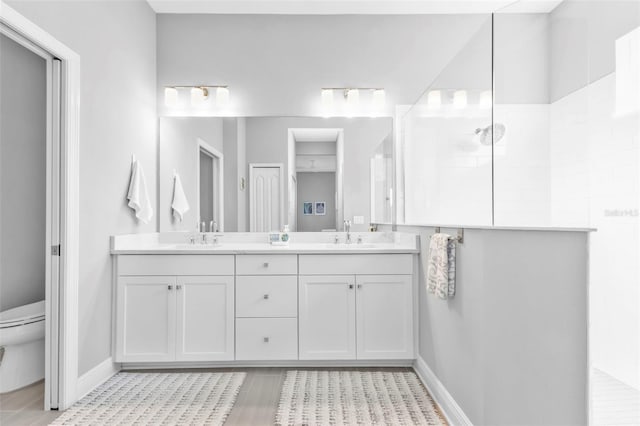 bathroom with walk in shower, vanity, and toilet