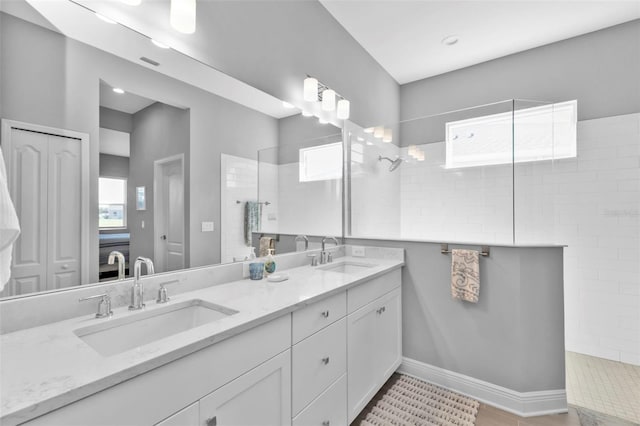 bathroom with vanity, a healthy amount of sunlight, and a tile shower