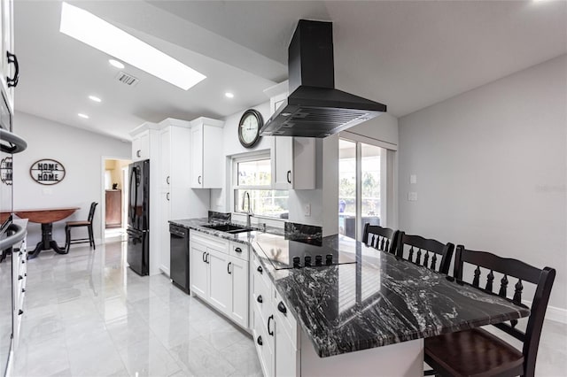 kitchen with sink, white cabinetry, dark stone countertops, island range hood, and black appliances