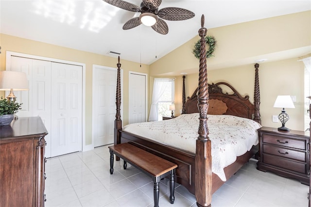 tiled bedroom with lofted ceiling, ceiling fan, and multiple closets