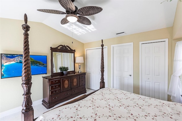 bedroom featuring ceiling fan, lofted ceiling, light tile patterned floors, and two closets