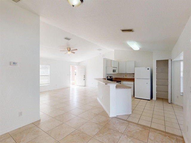 kitchen with lofted ceiling, white appliances, ceiling fan, white cabinets, and light tile patterned flooring