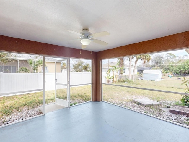 unfurnished sunroom featuring ceiling fan