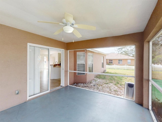 unfurnished sunroom featuring ceiling fan